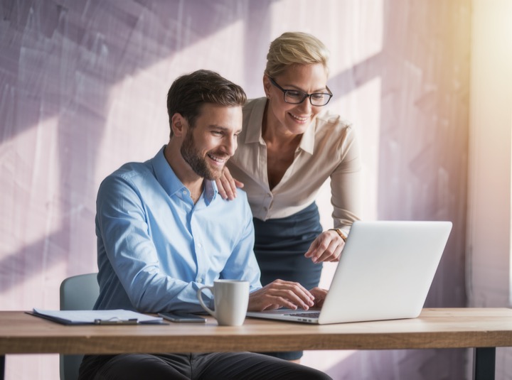 Two colleagues reviewing a draft on a laptop (illustrative image)